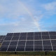 A rainbow over a field with solar panels.